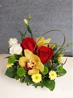 Cymbidium orchids, roses, lisianthus, pompoms, monkey grass and variegated pitt