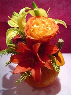 Yellow and red lillies, solidago, mini gerbera, circus roses, and pompoms in a pumpkin