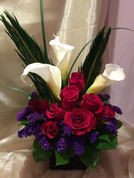 Calla lilies, roses, statice, sago palm, and monkey grass