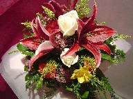 Stargazer, roses, freesia, solidago, waxflowers, and orange carnations