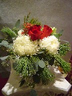 Roses, commercial mum, alstroemeria, pine, waxflowers, and seed eucalyptus